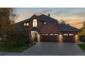 Charming brick home featuring an attached three-car garage and lush landscaping at dusk at 10346 E Crestridge Ln, Englewood, CO 80111