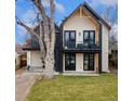 Stunning modern home with a white brick facade, black accents, balcony, and professionally landscaped yard at 1675 S Steele St, Denver, CO 80210