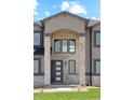 Stunning front entrance with a stone pillar archway, black framed windows, and trimmed green lawn at 2990 S Juliet Ct, Strasburg, CO 80136