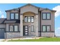 Gorgeous two-story home with a stone pillar entrance, black framed windows, and manicured lawn at 2990 S Juliet Ct, Strasburg, CO 80136