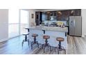 Kitchen with a large island, stainless steel appliances, dark cabinets, and sliding glass doors to outdoor space at 4783 S Wenatchee Cir, Aurora, CO 80015