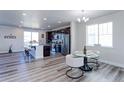 Open-concept kitchen and dining area with stainless steel appliances, modern light fixtures, and stylish wood floors at 4783 S Wenatchee Cir, Aurora, CO 80015
