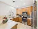 Bright kitchen featuring stainless steel appliances, wood cabinetry, and a window overlooking the neighborhood at 12912 Grant Cir # A, Thornton, CO 80241