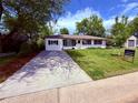 Beautiful home exterior showcasing a well-manicured lawn, a long driveway and lovely curb appeal at 4425 E Harvard Ave, Denver, CO 80222