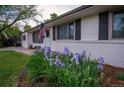 Charming home exterior with a well-maintained lawn and a garden with purple flowers in the front yard at 4425 E Harvard Ave, Denver, CO 80222