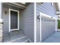 Home's front door entrance with a two-car garage and exterior lighting at 7686 Grady Cir, Castle Rock, CO 80108
