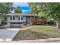 Charming gray home with a covered deck, attached garage and well-manicured lawn at 13610 W Dakota Pl, Lakewood, CO 80228