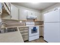 Well-lit kitchen with white cabinets, a double sink, and matching white appliances at 13606 E Bates Ave # 102, Aurora, CO 80014