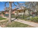 Charming home with a landscaped front yard enclosed by a black iron fence and mature trees at 2314 Dexter St, Denver, CO 80207