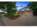 Beautifully landscaped home featuring a lush front yard and inviting curb appeal at dusk at 8935 W Swarthmore Dr, Littleton, CO 80123