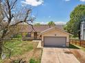 View of the home's front exterior, featuring a one car garage and well-manicured front lawn at 831 Sable Blvd, Aurora, CO 80011