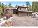 Spacious home with three-car garage, steps to front door, and serene views, blending modern design with natural surroundings at 5575 Jackpine Rd, Evergreen, CO 80439