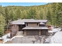 Attractive exterior featuring a three-car garage, grand entrance staircase, and well-maintained grounds in a serene setting at 5575 Jackpine Rd, Evergreen, CO 80439