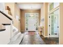 Inviting foyer with stone floors, staircase, natural light and access to another room with door with glass panes at 5575 Jackpine Rd, Evergreen, CO 80439