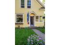 Charming home's front entrance with blue door, vibrant flower beds, and lush green lawn at 310 Judson St, Longmont, CO 80501