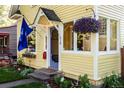 Close-up of the charming yellow home's front entrance, featuring a hanging flower basket at 310 Judson St, Longmont, CO 80501