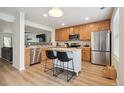 Open kitchen with stainless steel appliances, wood cabinets, an island and stylish bar stools at 371 Smith Cir, Erie, CO 80516
