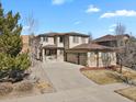 A tan two-story home with a three-car garage, brick accents, and a concrete driveway under a blue sky at 24269 E Arapahoe Pl, Aurora, CO 80016