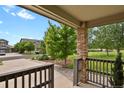View from the porch of this home with brick supports and a stained wood railing, overlooking the front lawn at 24269 E Arapahoe Pl, Aurora, CO 80016