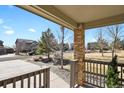Home's covered front porch with brick columns and wood railing, offering a view of the landscaped neighborhood at 24269 E Arapahoe Pl, Aurora, CO 80016