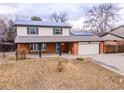 Inviting two-story home featuring solar panels, brick accents, and an attached garage at 6410 S Kendall St, Littleton, CO 80123