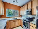 Modern kitchen featuring stainless steel appliances, orange walls and a window to the outside at 3230 Boulder Cir # 101, Broomfield, CO 80023