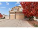 Charming two-story home with attached three-car garage and welcoming curb appeal with fall foliage at 15003 W 63Rd Ave, Arvada, CO 80403