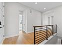 Bright hallway features sleek hardwood floors, a modern railing, and an airy, inviting atmosphere at 7293 Canyon Sky Trl, Castle Pines, CO 80108