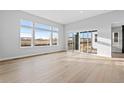 Bright living room featuring large windows, light hardwood floors, and sliding glass doors to the outside at 7293 Canyon Sky Trl, Castle Pines, CO 80108