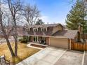 Inviting home featuring a large driveway, brick accents, mature trees, and well-kept landscaping at 7197 S Newland St, Littleton, CO 80128