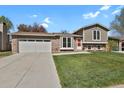 Well-maintained two-story home with brick and siding exterior and a green front lawn at 8001 S Estes St, Littleton, CO 80128