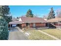 Attractive brick home with a carport, showcasing its well-kept lawn and welcoming front entrance, enhancing its appeal at 7081 Warren Dr, Denver, CO 80221