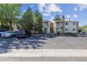 Exterior view of building with parking and mature trees, showcasing community living and convenience at 8555 Fairmount Dr # B202, Denver, CO 80247