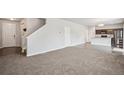 Open living room with carpet, adjacent kitchen, and stairs at 6104 Black Mesa Rd, Frederick, CO 80516