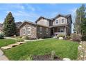 Charming two-story home with a stone facade, well-manicured lawn, and inviting front porch at 7963 S Valleyhead Way, Aurora, CO 80016