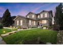Charming two-story home featuring stone accents, a welcoming porch, professional landscaping, and illuminated pathway at 7963 S Valleyhead Way, Aurora, CO 80016