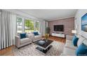 Bright living room featuring hardwood floors, a large window, and modern furnishings with a brick accent wall at 2571 S Birch St, Denver, CO 80222