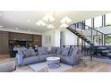 Open-concept living room with modern chandelier, sleek staircase, and gray sectional sofa at 1016 24Th St, Golden, CO 80401