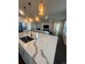 Modern kitchen featuring a large island with quartz countertops, pendant lighting, and open to the living area at 8163 S Valleyhead Way, Aurora, CO 80016