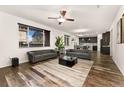 Open-concept living room and kitchen area with hardwood floors, ceiling fan, and comfortable gray sofas at 25127 E Maple Ave, Aurora, CO 80018