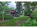 A view of the cozy home with mature trees and walkway leading to the front entrance at 1703 W Weaver Ave, Littleton, CO 80120