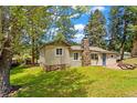 Exterior shot of a charming home with green lawn, stone foundation, and a stone chimney at 26351 Sheldon St, Kittredge, CO 80457
