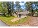 View of the front exterior featuring a charming home with a stone chimney and blue front door at 26351 Sheldon St, Kittredge, CO 80457