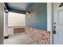 Inviting front porch featuring brick accents, a hanging light, and space for seating at 10364 Ravenswood Way, Highlands Ranch, CO 80130