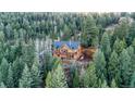 A beautiful aerial view of the house showcases its balconies and is surrounded by a lush forest at 1055 Saddleback Dr, Evergreen, CO 80439