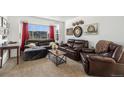 Spacious living room features a large window, leather furniture, and tasteful decor at 17464 Crestview Ct, Monument, CO 80132