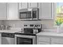 Stainless steel oven, range, microwave and dishwasher are set amongst white countertops and cabinets at 957 Newton St, Denver, CO 80204