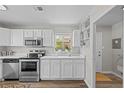 Well-lit kitchen featuring stainless steel appliances, white cabinets, and wood-look flooring at 957 Newton St, Denver, CO 80204
