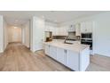 Modern kitchen with white cabinets, stainless steel appliances, large island, and hardwood floors at 20 Leafy Aster Ln, Castle Rock, CO 80104