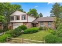 Charming brick home with a two-car garage, well-maintained lawn, and mature landscaping at 4677 S Wolff St, Denver, CO 80236